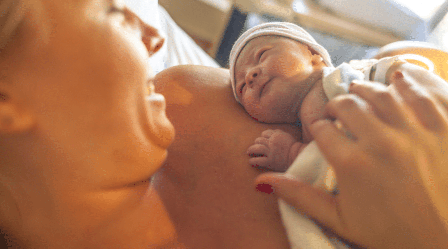 Mother with newborn baby son lying in bed
