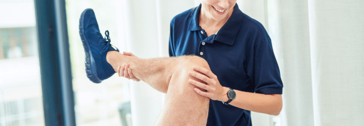 Elderly man on Physiotherapy table working out, doctor lifting leg to help exercise hip and improve mobility