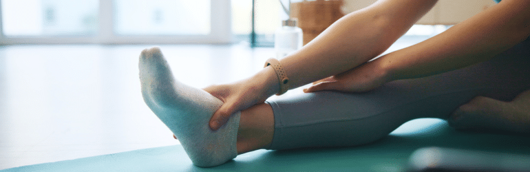 Woman, hands or stretching foot on mat in home for flexibility for physical health, fitness training or exercise