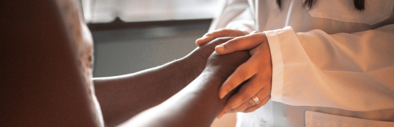 Female doctor holding hands of her patient at hospital room
